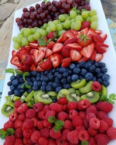 a platter filled with lots of different types of berries and kiwis on top of each other