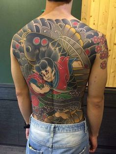 the back of a man's body with tattoos on it and an image of a geisha