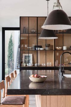 a kitchen with an island, sink and hanging light over the counter top in front of it