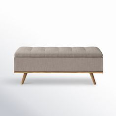 an upholstered bench with wooden legs and a light colored fabric seat pad on top