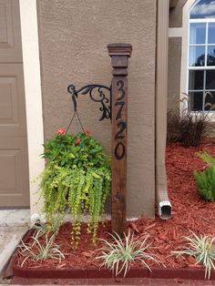 a wooden pole with plants growing out of it next to a house and a door