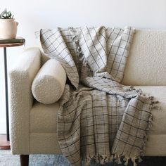 a couch with a blanket on top of it next to a table and potted plant