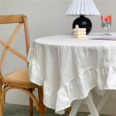 a table with a white cloth on it next to a wooden chair and a lamp