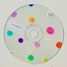 a cd with smiley faces on it sitting on a white surface and surrounded by colored stickers