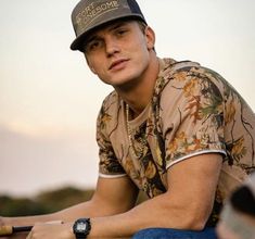 a man sitting on the ground wearing a hat