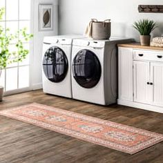 a washer and dryer sitting in a room next to a rug on the floor