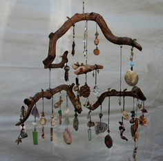 a wind chime hanging from a tree branch with beads and shells attached to it