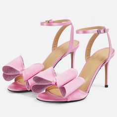 Elevate your style with these pink satin heeled sandals. Featuring an open toe design, elegant bow detail, shimmering crystal embellishments, and a secure ankle strap, perfect for chic women. Color: Pink Heel Type: Stiletto heel Heel height: 4" / 100 mm approx Product measurements were taken using size 8. Please note that measurements may vary by size. Toe: Open toe Adjustable ankle strap design Faux crystal bow embellishment Handcrafted US sizing. Fits true to size. Pink High Heel Sandals With Bow, Pink Open Heel Heels With Bow, Pink Heels With Satin Bow For Spring, Pink Open Toe Heels With Bow, Pink Ankle Strap Heels With Bow Straps, Pink Bow Sandals For Evening, Pink Party Heels With Bow Straps, Summer Pink Heels With Satin Bow, Pink Wedding Sandals With Bow