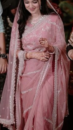 a woman wearing a pink sari and holding her hands together