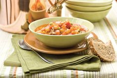 there is a bowl of soup on the table with two slices of bread next to it