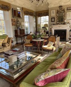 a living room filled with furniture and a fire place under a chandelier above a glass top coffee table