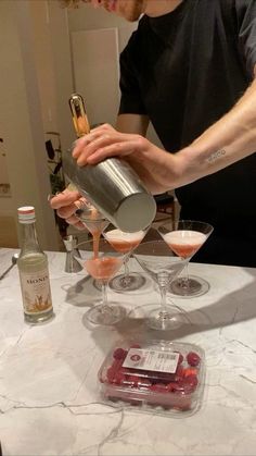 a man pouring drinks into glasses on top of a marble table with liquor bottles and shots