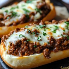 two hot dogs covered in cheese and meat on top of bread with parmesan toppings