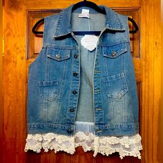 an old jean vest with lace on the bottom and buttons down at the back, hanging on a wooden door