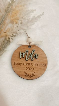 a baby's first christmas ornament hanging on a white blanket with feathers