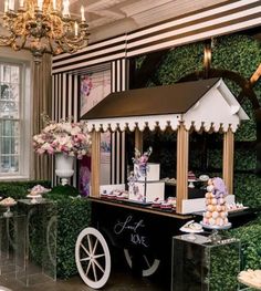 an elaborately decorated dessert cart in front of a window with flowers and greenery