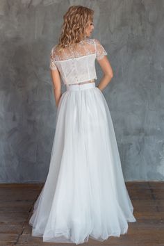 a woman in a white wedding dress standing on a wooden floor with her back to the camera