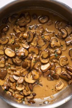 a pan filled with mushrooms and sauce on top of a table