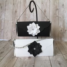 two black and white purses with flower decorations on the front, one is made out of paper