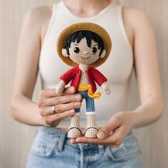 a woman holding a small doll in her hands with a straw hat on top of it