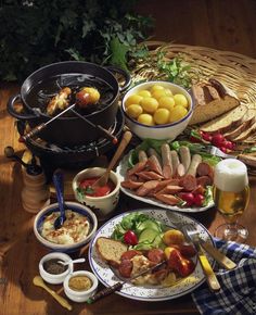 a table topped with lots of food next to a basket filled with bread and fruit