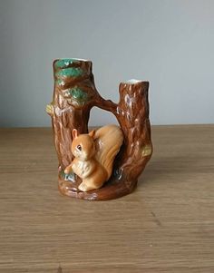 a ceramic figurine of a squirrel in a tree stump