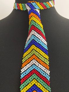 👔 Absolutely stunning beaded tie, handmade by highly skilled Zulu women in Kwa-Zulu Natal, South Africa. 👔 This gorgeous tie is made up of thousands of glass beads, each one threaded by hand to make an absolutely beautiful tie in a colourful chevron design. 👔 The tie is fastened with a single beaded loop and ball clasp and lies flat on the chest. 👔 Remarkable beadwork - exceptionally high quality and real showstopper.  If you're looking to make a statement, this tie is for you! 👔 Neck measurement 35cm (14in). Length 29cm.  Width 5.5cm 👔 See my other listings for alternative sizes and colours. More about us.... Our products are all hand-made, by artists and crafters in South Africa. We source suppliers with the highest quality standards. Where possible, we show images of the exact pro Adjustable Multicolor Beaded Bracelets For Wedding, Ceremonial Multicolor Beaded Necklaces, Traditional Adjustable Beads For Wedding, Bohemian Multicolor Beaded Bracelets For Weddings, Traditional Multicolor Beaded Bracelets For Party, Multicolor Large Beads For Wedding, Bohemian Tiny Beads For Wedding, Bohemian Multicolor Wedding Beads, Bohemian Beaded Bracelets With Colorful Beads For Weddings