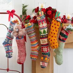 christmas stockings hanging from a rack in front of a fire place with candles and decorations