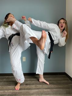 two women are doing karate moves in a room with blue walls and wood flooring