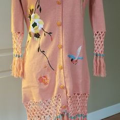 This Is A Beautiful Brand New Storybook Knits Long Tunic Like Sweater. It Features Flower And Bird Embroidery, Beaded Double Button With Under Button Closure, And Beautiful Crocheted Trim With Beaded Fringe On The Bottom Of The Sweater And Sleeves. It Says Xs But They Appear To Run On A Little Larger. The Armpit To Armpit Measures 18 Inches, As Does The Hip. The Length Is 28 Inches Of The Actual Sweater, 34 Inches To The Bottom Of The Fringe. It Would Look Fantastic With Leggings And Boots! Pink Embroidered Long Sleeve Cardigan, Fitted Embroidered Pink Cardigan, Pink Embroidered Fitted Cardigan, Fitted Pink Embroidered Cardigan, Spring Pink Knit Sweater, Pink Knitted Cotton Sweater, Pink Cotton Knitted Sweater, Pink Knit Cardigan For Spring, One Size Pink Knit Sweater