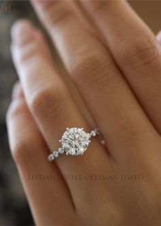 a woman's hand with a diamond engagement ring on her left hand and the middle finger