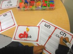 two children's hands are writing letters on their worksheets