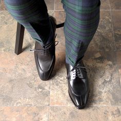 a person in striped pants and black shoes standing on a tile floor next to a chair