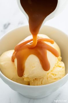 ice cream with caramel sauce being drizzled over it in a bowl