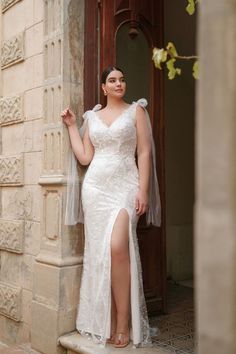 a woman in a wedding dress leaning against a wall