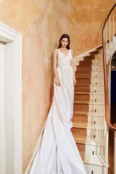 a woman in a white dress is standing on the stairs