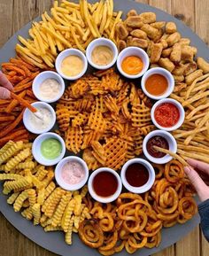 a platter filled with lots of different types of fries and dipping sauces on top of it