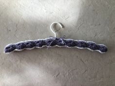 a crocheted purple and white tie hanging from a hook