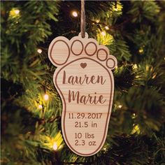 a personalized ornament hanging from a christmas tree with lights in the background