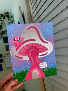 a person holding up a card with a pink mushroom on it