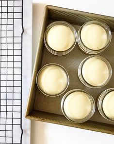 a muffin tin filled with white frosting next to a cooling rack on a counter