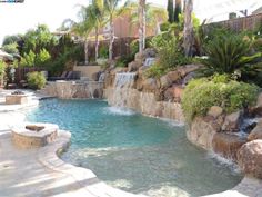 an outdoor swimming pool with waterfall and rocks