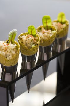 four cones filled with food sitting on top of a black table next to each other