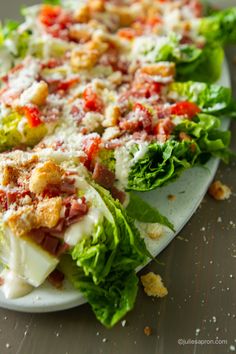 lettuce and tomato salad on a plate with crumbs scattered around it