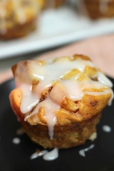 a muffin with icing sitting on top of a black plate