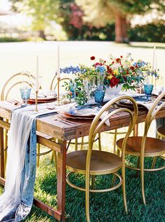 an outdoor table set with flowers, candles and place settings for two people to sit at