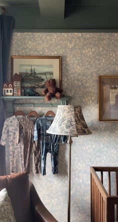 a baby's room with clothes hanging on the wall and a teddy bear next to it