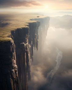 a man standing on the edge of a cliff in the middle of foggy mountains