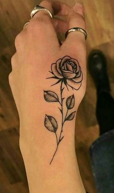 a woman's wrist with a rose tattoo on the left side of her arm