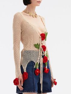 a woman in a short skirt with roses on the side and an open knit top